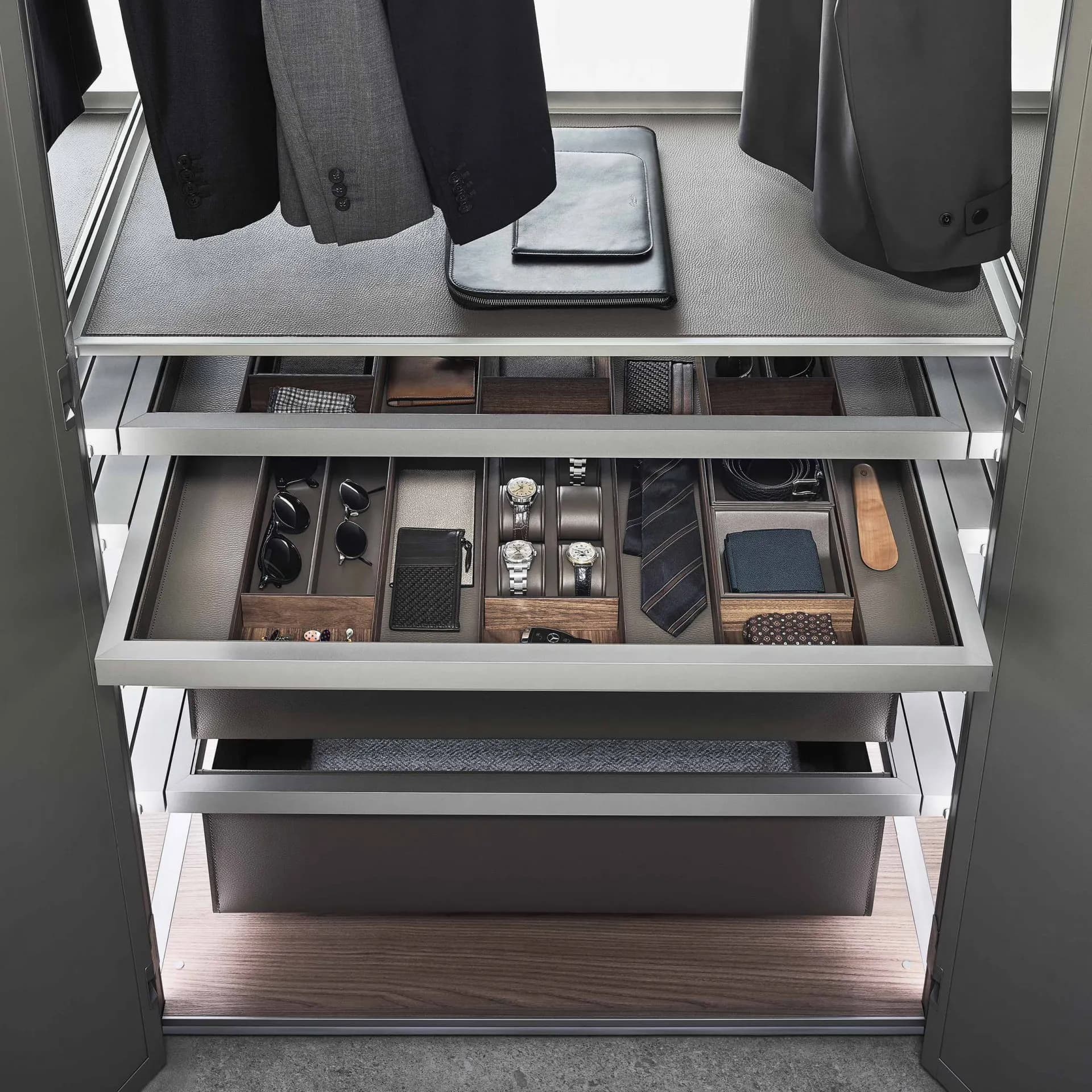 Pull-out drawers with leather-lined trays holding watches, ties and folded accessories